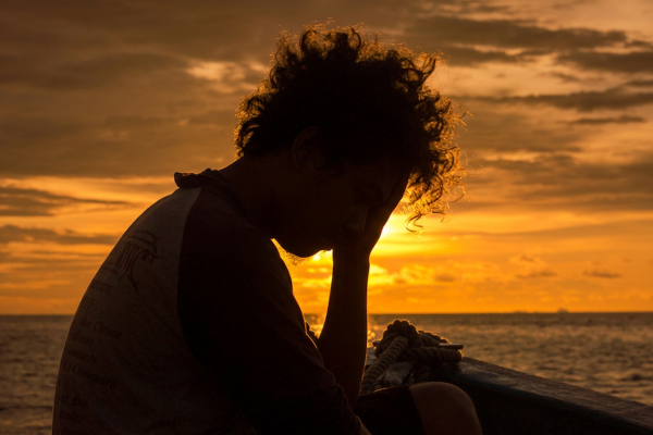 Man at sunset with head in hands